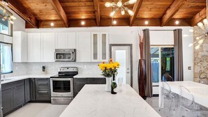 A modern kitchen with white cabinets, stainless steel appliances, and a marble countertop. - Mid-Century Chic | Pool & Hot Tub | Skyview Loft (Fort Lauderdale)