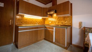 A compact kitchen with wooden cabinets, a built-in oven, and a tiled backsplash. - 302A Apartments Garni Zilli (Laion)
