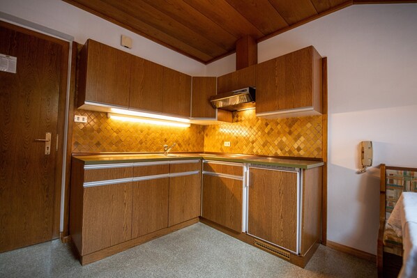 A compact kitchen with wooden cabinets, a built-in oven, and a tiled backsplash.