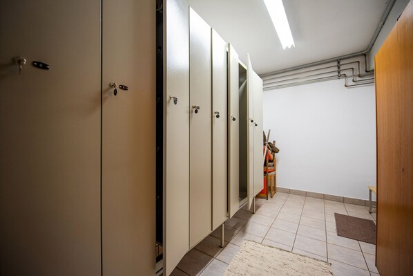 A row of lockers with a bench and a trash bin in a hallway. - 302B Apartments Garni Zilli (Laion)