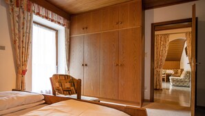 A bedroom with a bed, wooden wardrobe, and a chair.