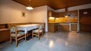 En matplats med en träbänk och ett träbord, ett kök med träskåp och en taklampa.