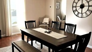 A dining room with a dark wooden table, six chairs, and a large wall clock. - Central House
Home Away From Home! (Bluffton)