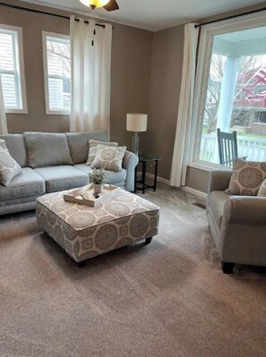 Relax in this stylish living room with a large window, grey sofa, and matching ottoman.