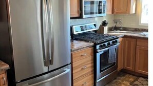 A kitchen with stainless steel appliances, wooden cabinets, and a tiled floor. - Central House
Home Away From Home! (Bluffton)