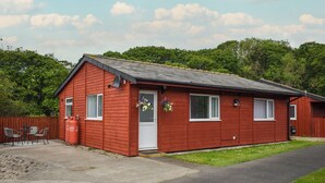 Eine rote Holzhütte mit weißer Tür, Fenstern und einer kleinen Veranda.