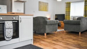 Eine moderne Küche mit Einbauofen und Essbereich mit zwei grauen Sofas und einem Holztisch.