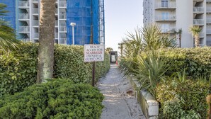 Un camí que condueix a un edifici amb un senyal que indica accés a la platja només per a propietaris i hostes.