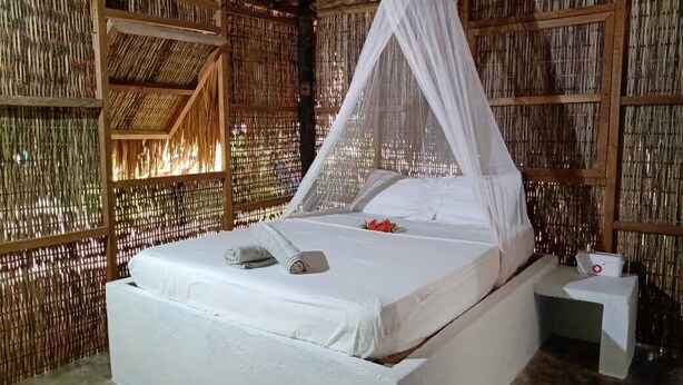 A room with a bed, a nightstand, and a mosquito net. - Las Palmeras (Rosario Islands)