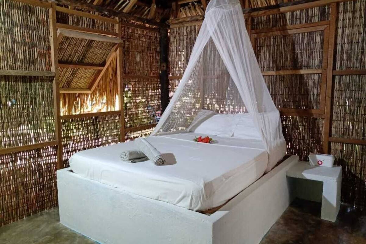 A room with a bed, a nightstand, and a mosquito net.
