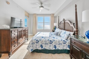 A bedroom with a bed, a dresser, a television, a ceiling fan, and a window with a view. - Aqua 1003 | Beachfront Getaway (Panama City Beach)
