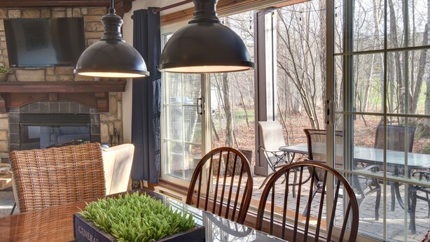 Un comedor con chimenea de piedra, sillas de mimbre y una mesa con un centro de mesa decorado con plantas.