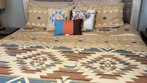 Een bed met een geborduurde sprei en meerdere kussens.