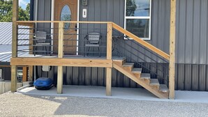 Een gebouw met een houten trap die leidt naar een balkon met twee stoelen.