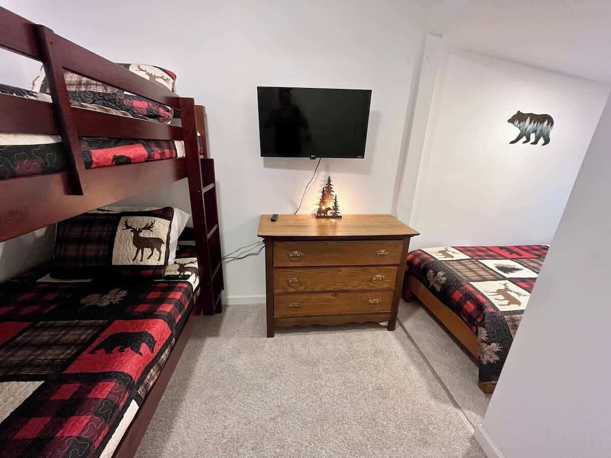 Una habitació amb lliteres, una petita cuixa de fusta, una televisió i un adhesiu mural de forma d'ós.