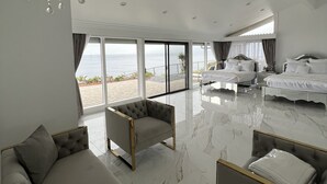 A spacious bedroom with a large bed, a sofa, and a chandelier.
