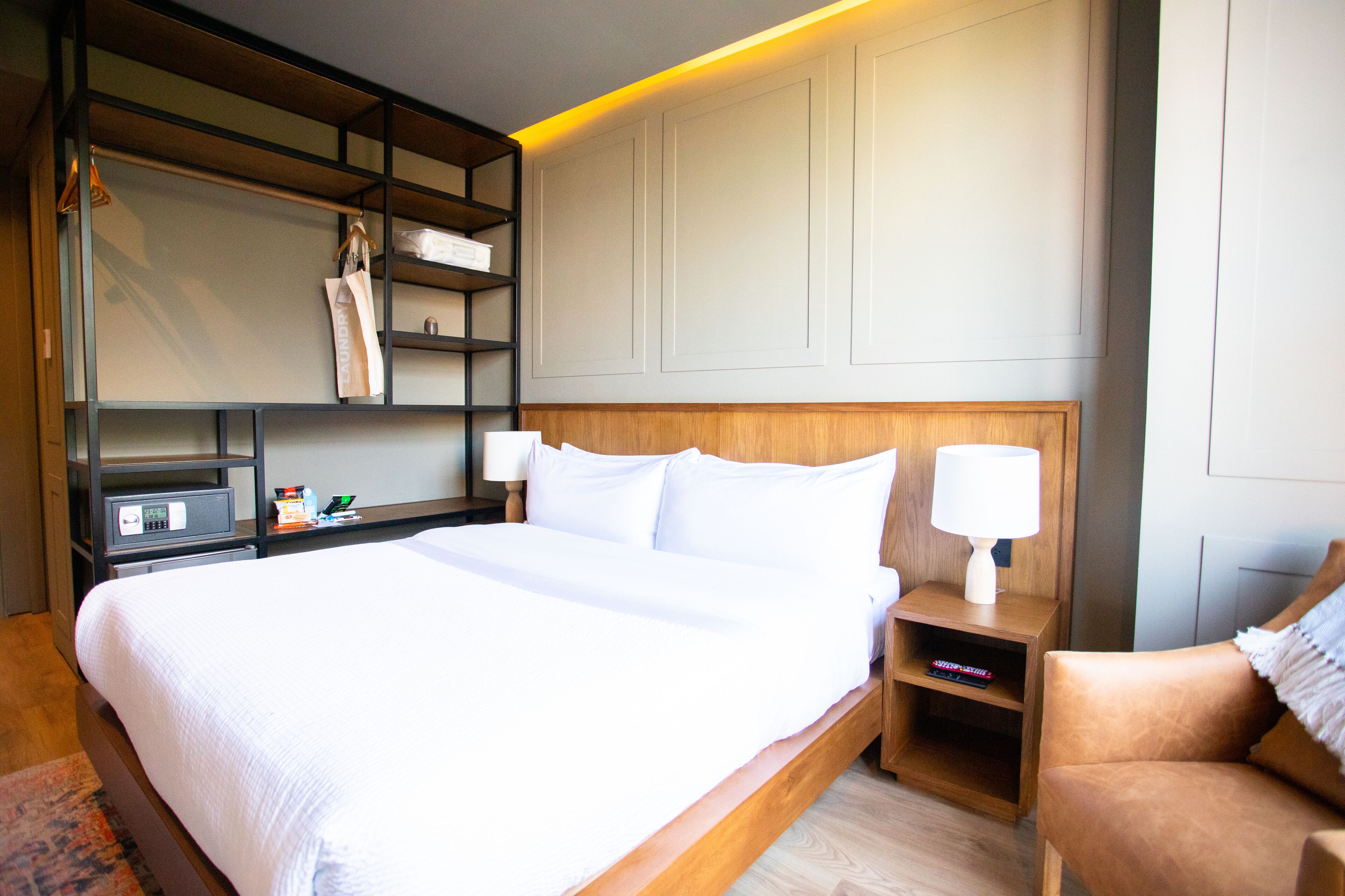 A neatly made bed with white linens, a wooden headboard, and a bedside table with a lamp.