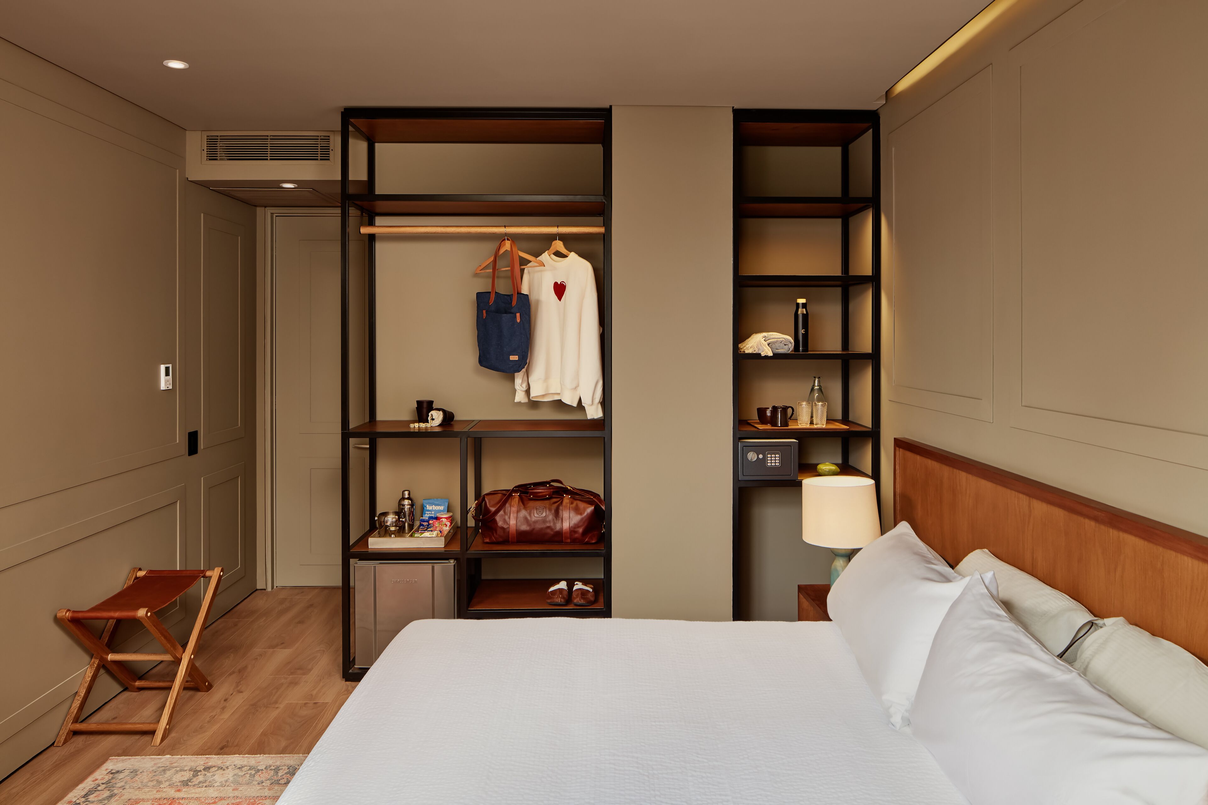 Una habitación de hotel con cama, armario, escritorio y silla.