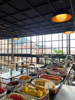 Un'area buffet con diversi cibi e vista sulla città attraverso ampie finestre.