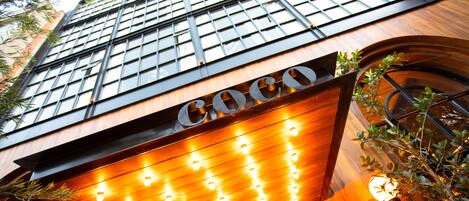 Un edificio con un evidente cartello 'Coco', ampie finestre e facciata in legno.