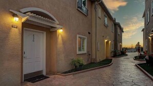 A residential street with houses, a paved walkway, and a sunset sky.