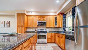 A modern kitchen with wooden cabinets, stainless steel appliances, and granite countertops.