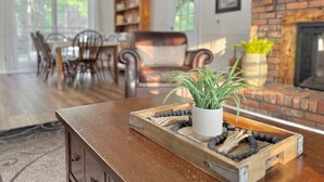 A cozy living room with a wooden coffee table, a fireplace, and a bookshelf. - Pond House on the Plains, Auburn, Firetruck rides (Opelika)