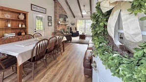 A dining area with a long table, wooden chairs, and a brick fireplace. - Pond House on the Plains, Auburn, Firetruck rides (Opelika)