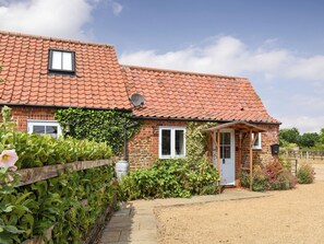 A brick house with a tiled roof, a front door, and a small porch.