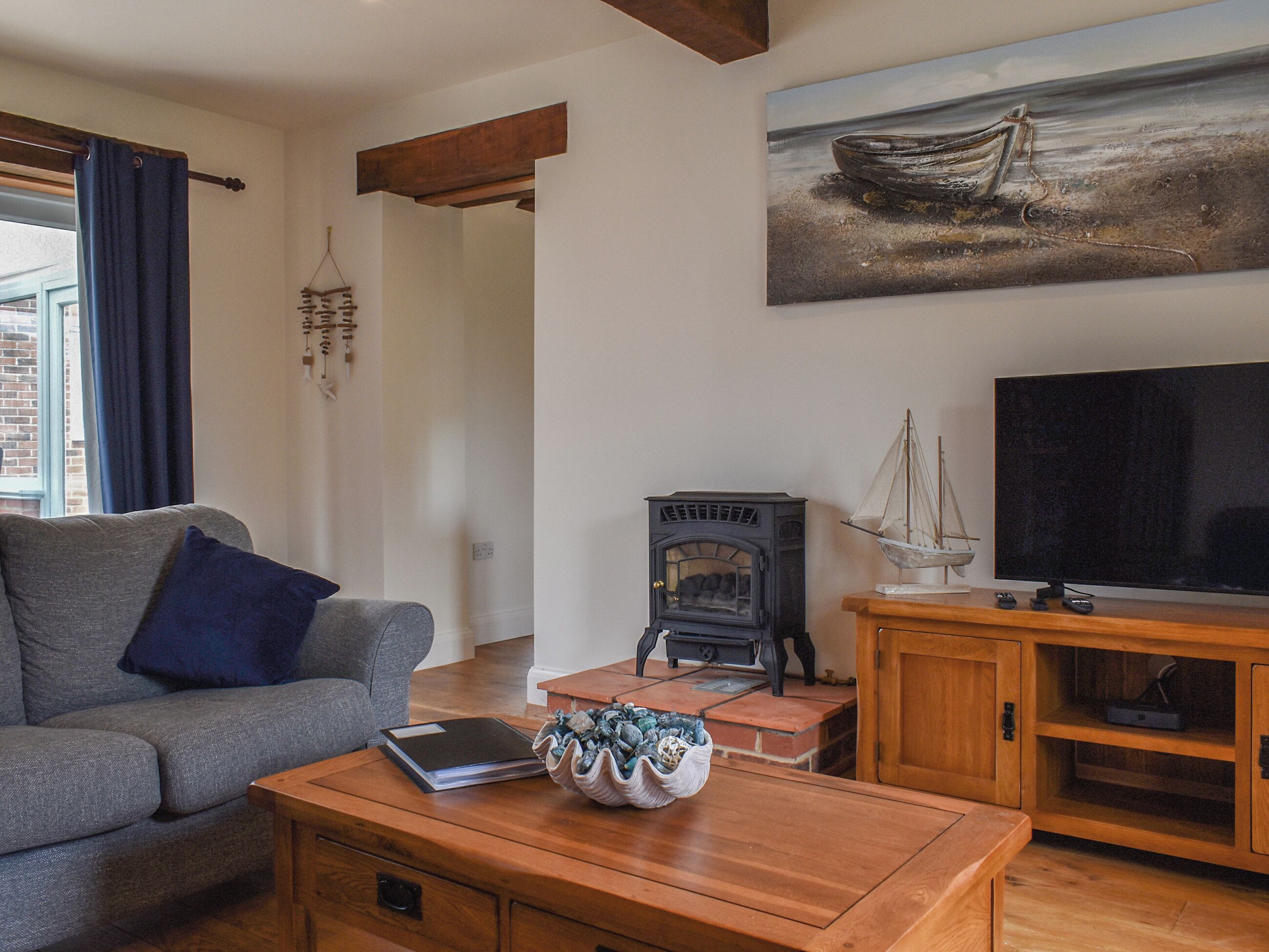 Ein Wohnzimmer mit Sofa, Kamin, Fernseher und einem Bild an der Wand.