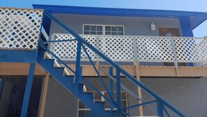 Eine blaue Treppe führt zu einem Balkon mit einem weißen Gittergeländer.
