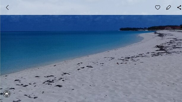 Ein Strand mit klarem, blauem Wasser und weißem Sand.
