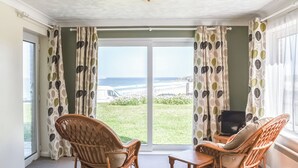 A room with a view of the beach, wicker chairs, a small table, and a ceiling light. - Apartment 1 Waterrs Edge (Newquay)