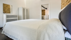 A bedroom with a bed, a wardrobe, and a mirror on the wall. - Loft in the old Town (Alghero)