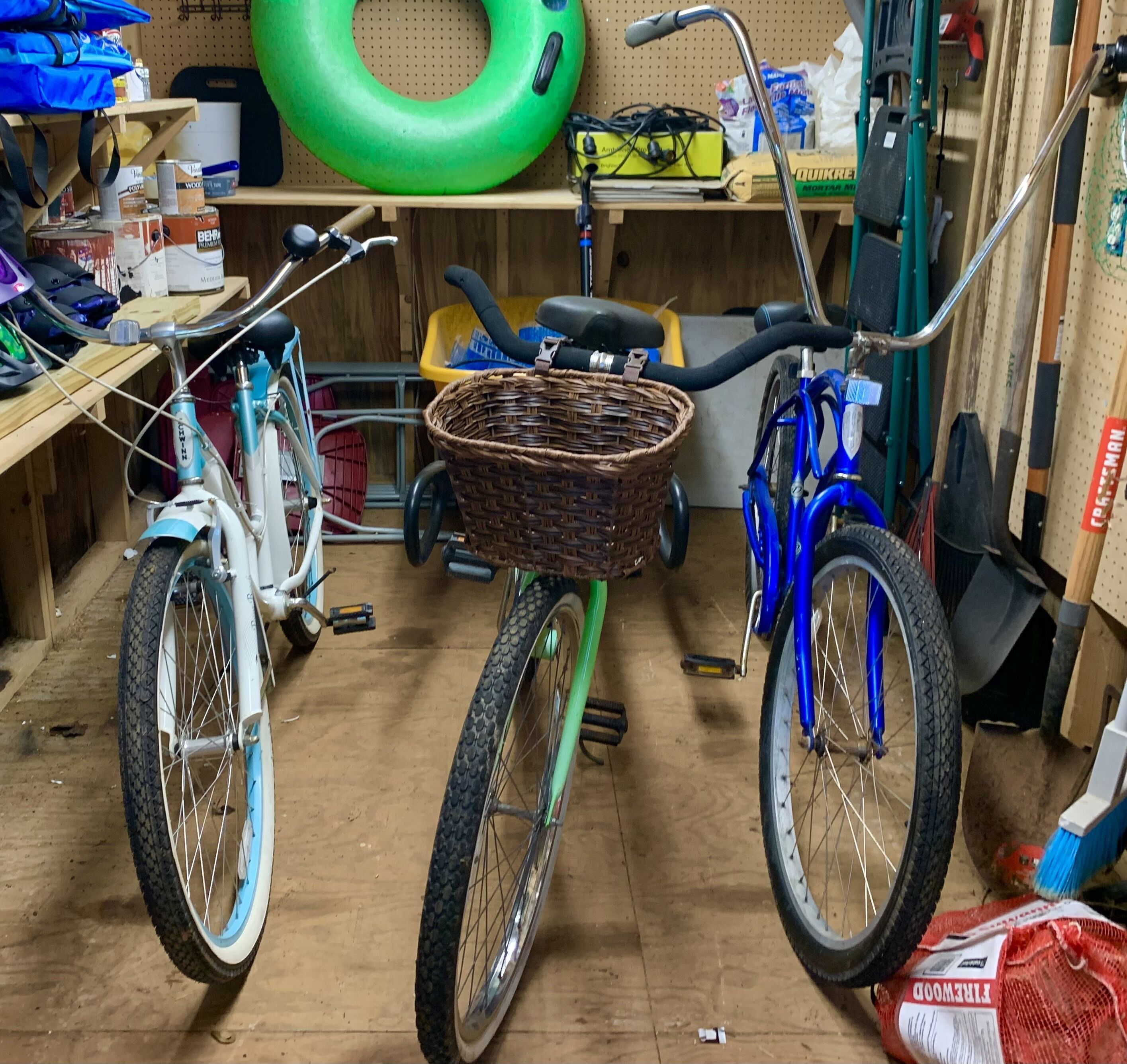 Una bicicleta con una cesta en el centro de una habitación desordenada con diversos objetos y herramientas.