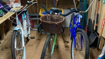 Una bicicleta con una cesta en el centro de una habitación desordenada con diversos objetos y herramientas.