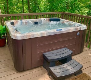 A hot tub with a wooden deck and a step for access.