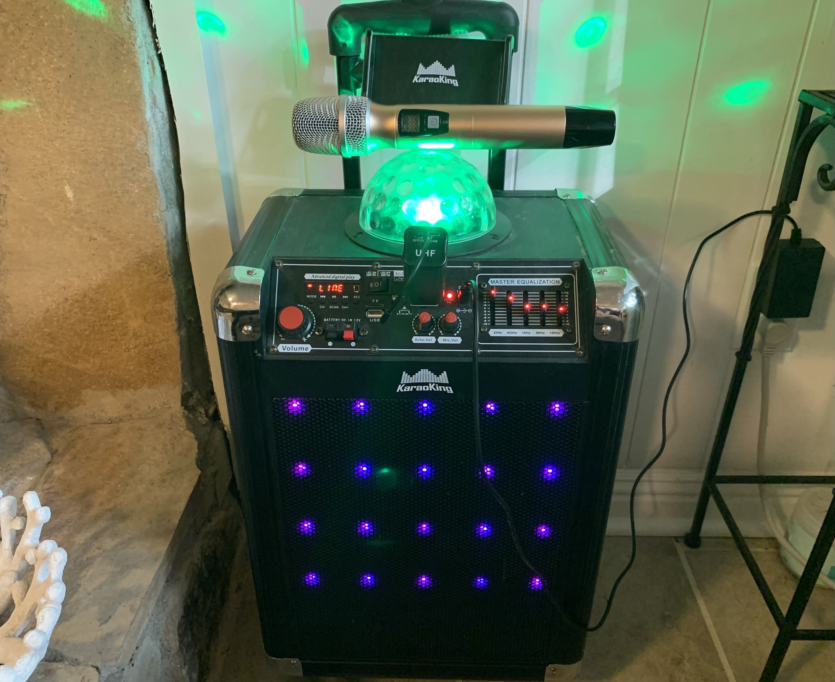 Sistema de karaoke con un micrófono, una luz verde y un panel de control con varios botones e indicadores.