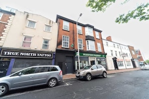 A street view with buildings, including a pharmacy and a tattoo shop. - Jesouth Exquisite Suite Dazzling Chic Centre (Kingston upon Hull)