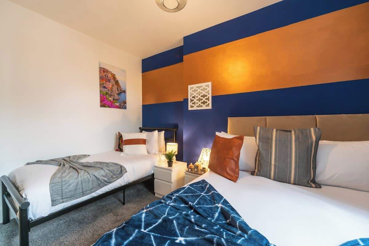 A hotel room with two beds, a nightstand, a lamp, and a wall with a geometric pattern.