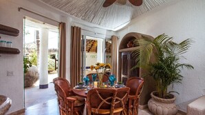 A dining area with a round table, wicker chairs, and a potted plant. - Beautiful view of the arch, Club Cascadas suite with kitchen. (Cabo San Lucas)