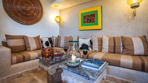 A cozy living room with a sofa set, a coffee table with drinks and a candle, and wall art. - Beautiful view of the arch, Club Cascadas suite with kitchen. (Cabo San Lucas)