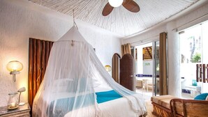 A bedroom with a bed covered by a white canopy, a bedside table with a lamp, and a view of the outside through a glass door. - Beautiful view of the arch, Club Cascadas suite with kitchen. (Cabo San Lucas)