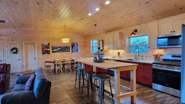 Un'ampia cucina con mobili in legno, un'area pranzo con tavolo e sedie, e un soggiorno con divano e camino.