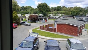 A view of a parking lot with several cars, a red building, and a row of mobile homes. - Kingfisher Cottage Caernarfon-river rambling & relaxing, in a beautiful setting  (Caernarfon)