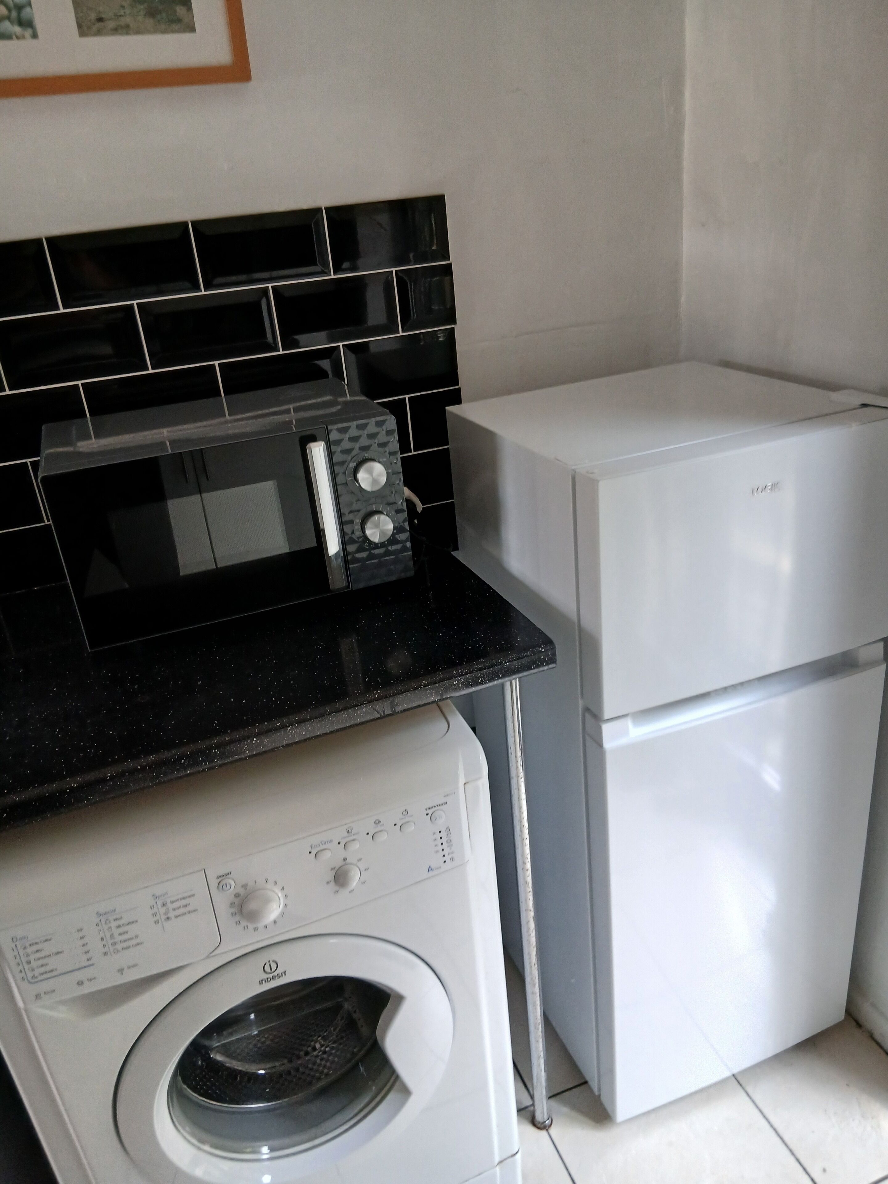Une cuisine compacte équipée d’un lave-linge, d’un four à micro-ondes et d’un réfrigérateur.