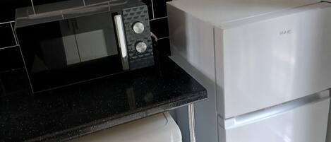 Une cuisine compacte équipée d’un lave-linge, d’un four à micro-ondes et d’un réfrigérateur.