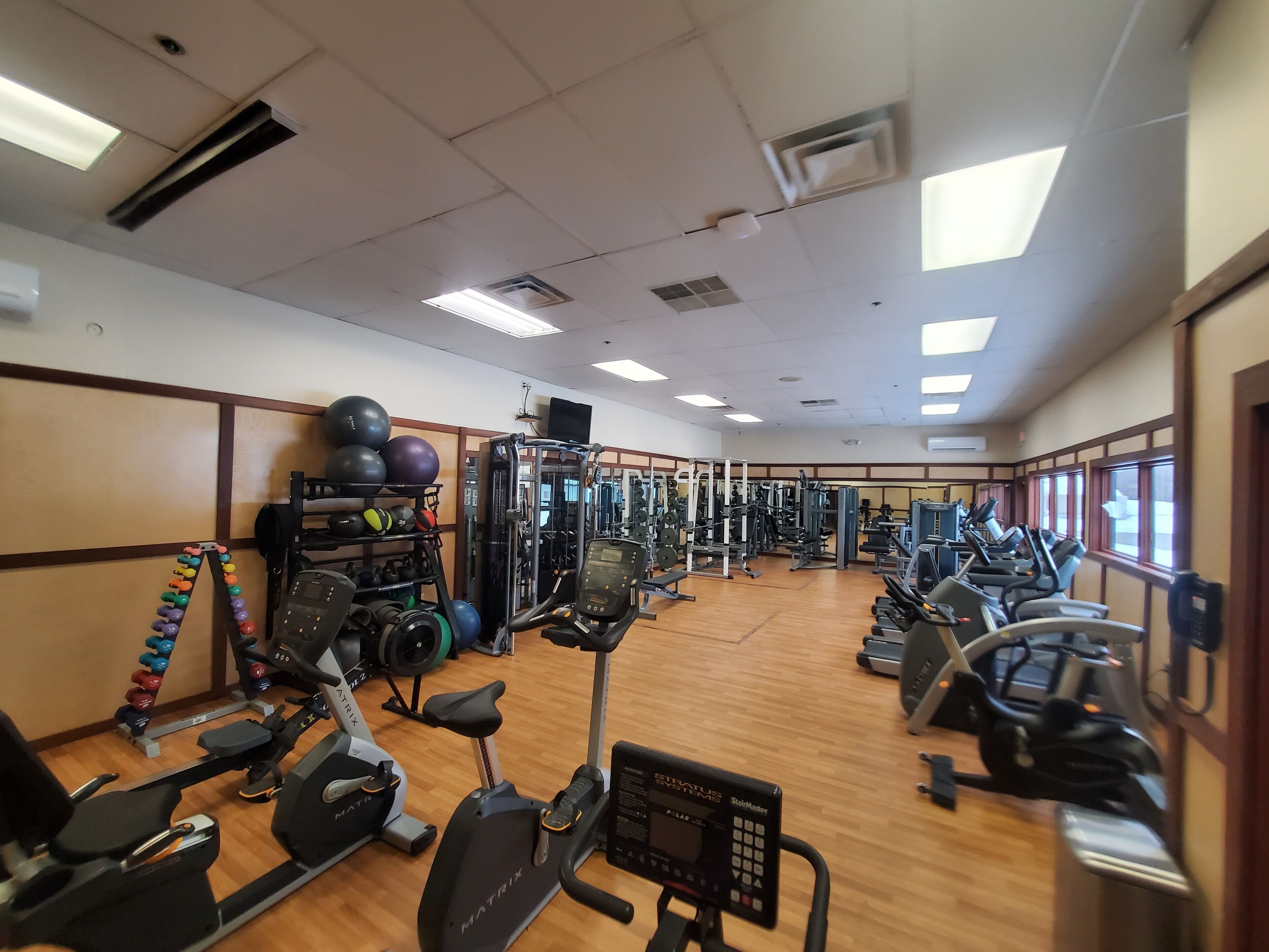 Uma academia com diversos equipamentos de exercício, incluindo esteiras, elípticos e estações de musculação.