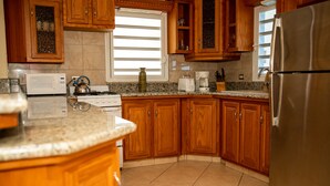 A kitchen with wooden cabinets, a stainless steel refrigerator, a microwave, a stove, and a coffee maker.