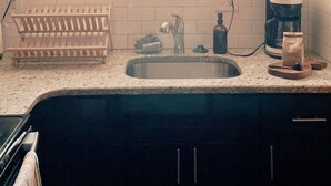 A kitchen with a window, potted plants, a sink, and a coffee maker. - CoralXscape: curated 2 bedroom in Philly near everything! (Philadelphia)